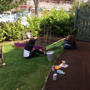 Two girls painting outdoor furniture