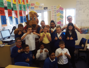 A class of children and Roary give their thumbs up