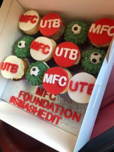 Cakes bearing the M F C and U T B wording together with text which says M F C Foundation hashtag smashed it