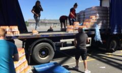 M F C Foundation staff and M F C staff unload bottles of orange from a lorry