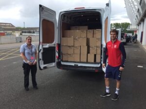 M F C Foundation's Ollie helps load a van with crisps